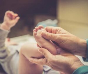 Immagine di una mamma che dà un massaggio ai piedi di un bambino, illustrando i benefici del massaggio ai piedi di mamma