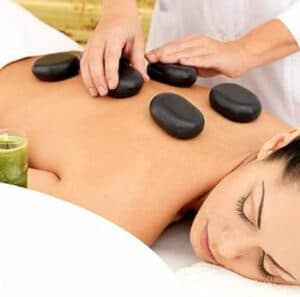 Foto di una donna che riceve un massaggio caldo con pietre per alleviare la tensione muscolare e lo stress