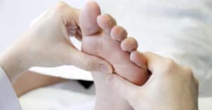 Immagine di un massaggiatore professionista che esegue un massaggio riflessologia plantare ai piedi del cliente